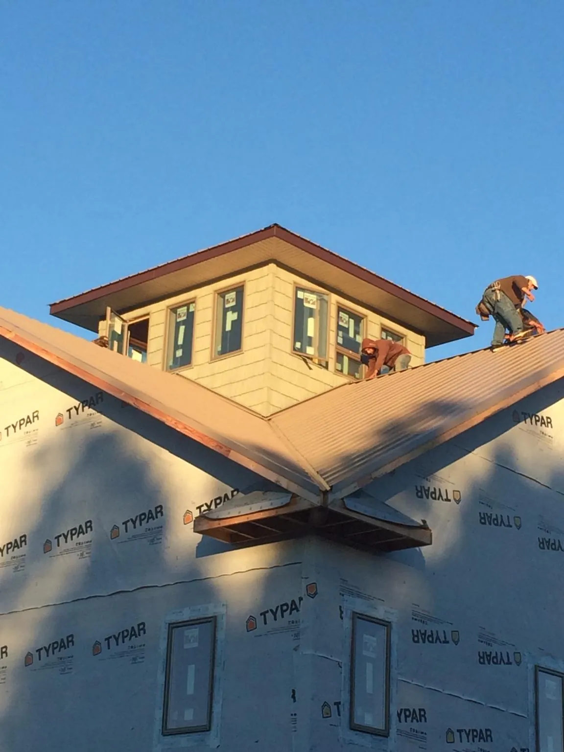 Roofers working around a rooftop cupola on a new metal roof at sunset — Roof Waterproofing in Marco Island by Roofing Brothers